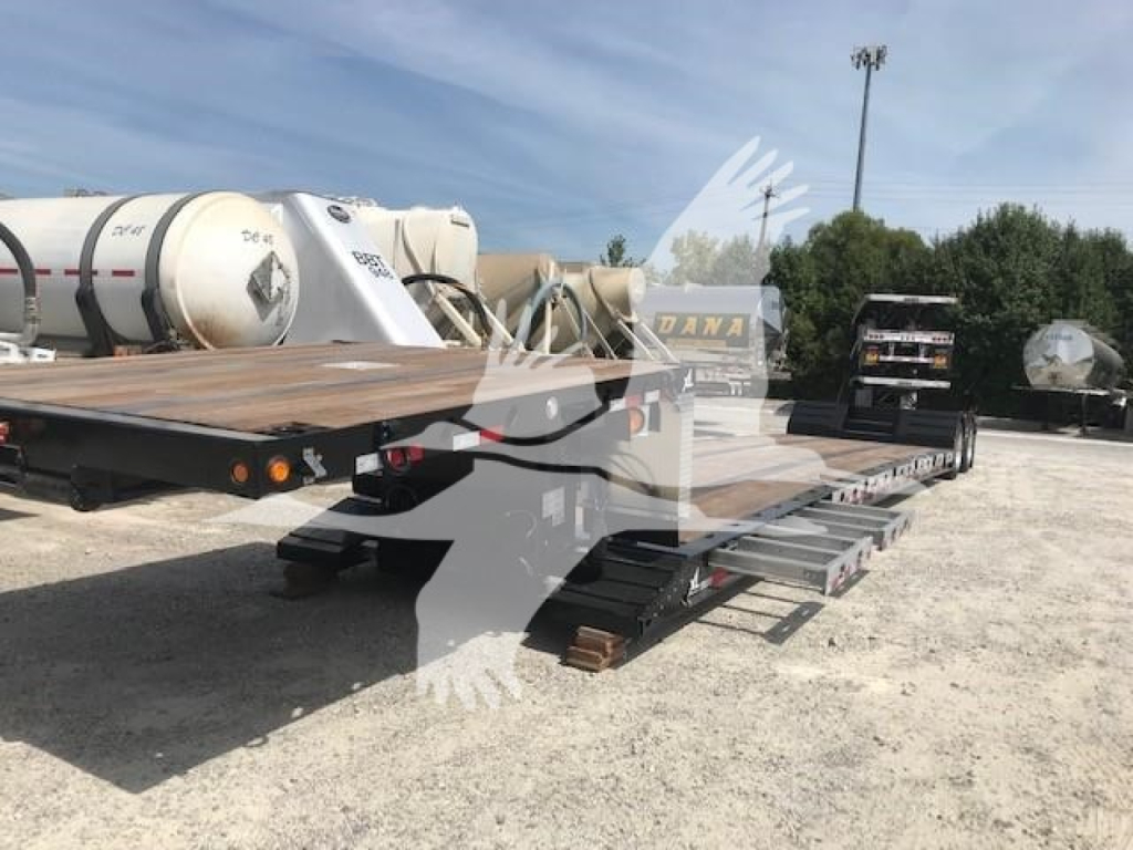 Flatbed trailer viewed from rear-left showing a long lowboy deck, dual rear axles, and ramps with metal steps.