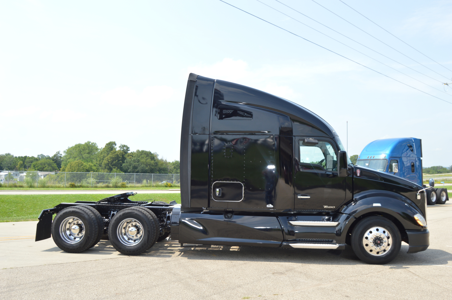 Kenworth T680 tractor in profile showing black sleeper cab with chrome wheels and dual rear axles.