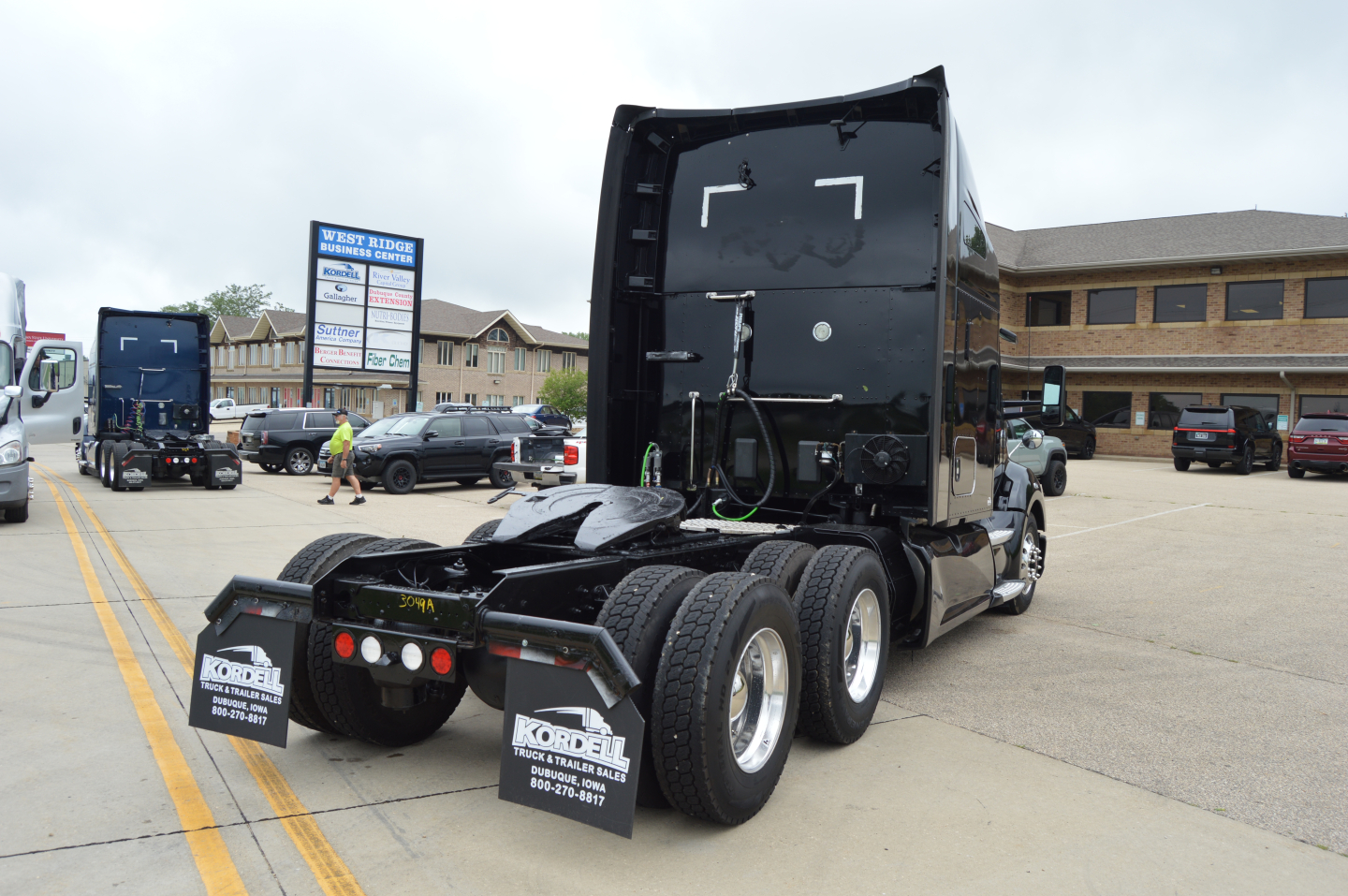 Kenworth T680 tractor unit rear view with fifth wheel and dual rear axles, cab back, wheels, and mud flaps.