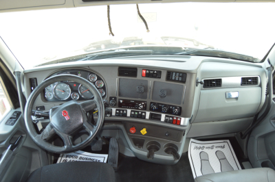 Kenworth T680 dash view showing steering wheel, instrument cluster, and center console in truck cab.
