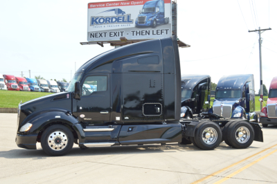 Kenworth T680 tractor unit in service lot showing black exterior and sleeper cab with 3-axle configuration