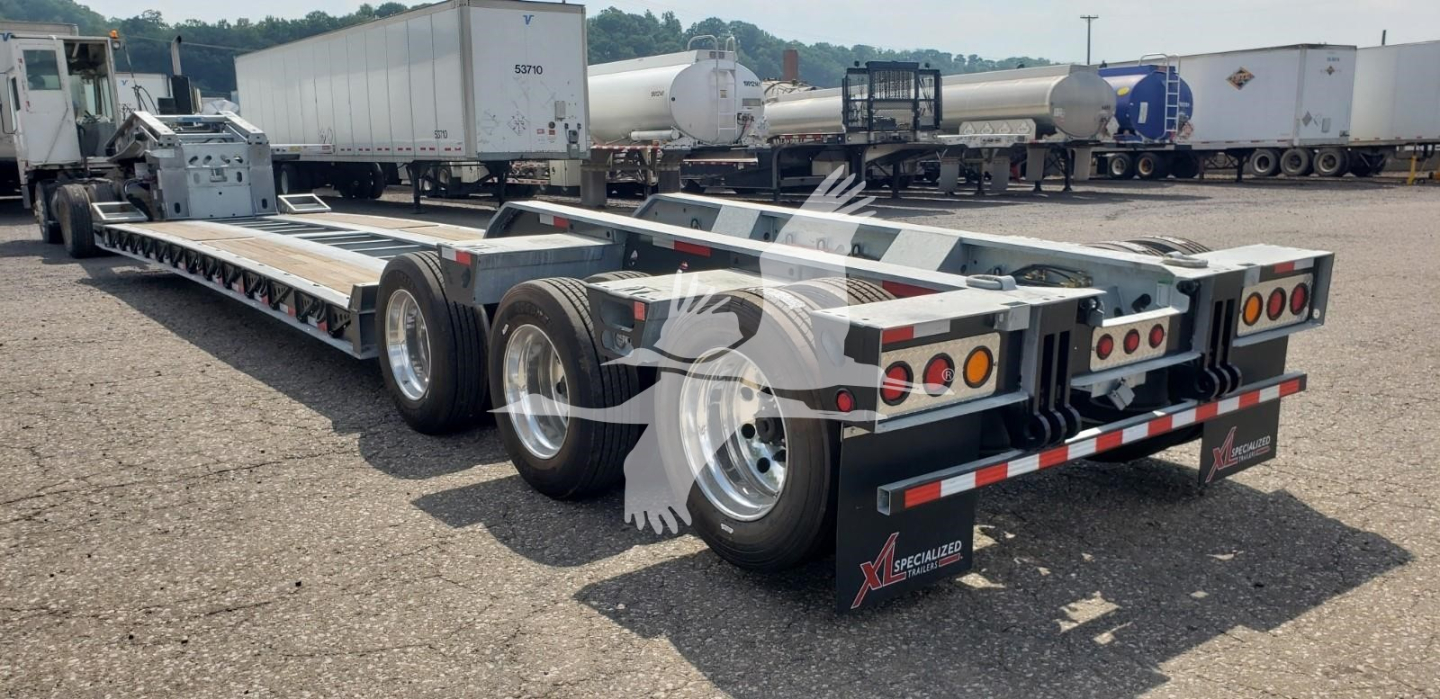 Trailer chassis in a lot showing a lowboy 3-axle setup with LDH 15-inch wheels and rear lighting; branding and reflective tape visible.