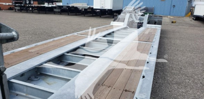 Trailer deck showing galvanized 55-ton lowboy with wooden planks and steel frame, long flatbed with cutouts and gooseneck area.