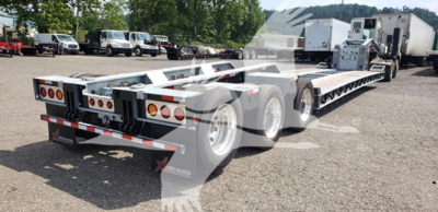 Trailer rear and side view showing a 55-ton lowboy trailer with long deck and multi-axle configuration; no visible text readable on image.