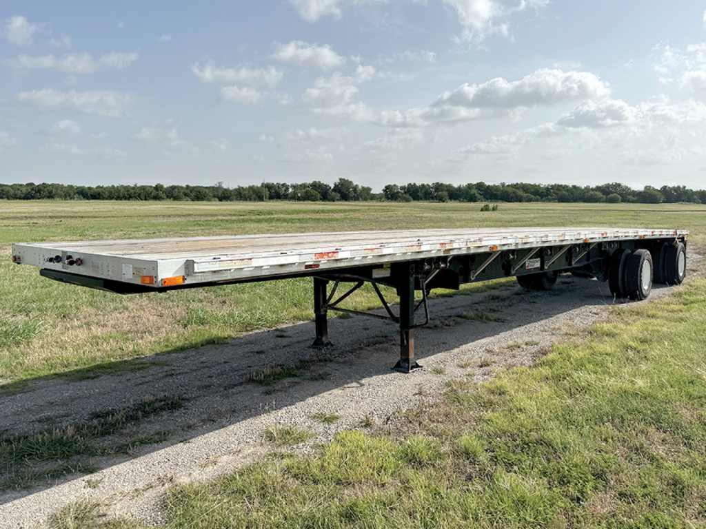 Flatbed trailer in field showing extended deck and support legs with wheels at rear. 2009 Transcraft Eagle trailer, VIN 1TTF4820491086211, stock 553138.