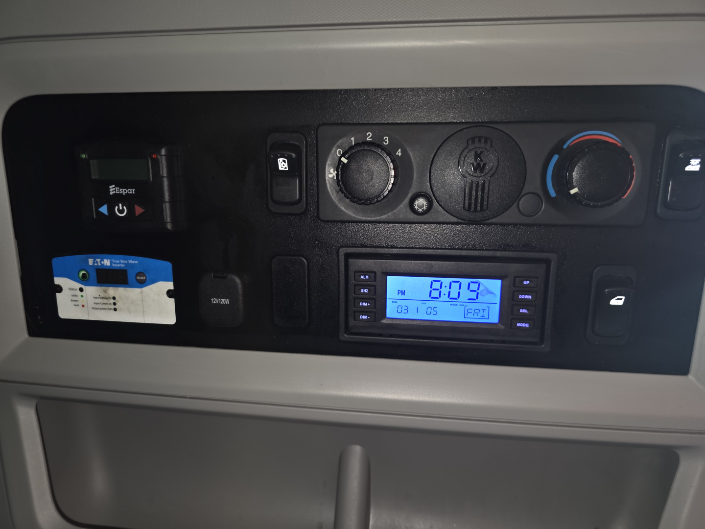 Kenworth T680 dash panel showing climate controls, digital clock, USB/aux ports, and storage with a blue display screen.