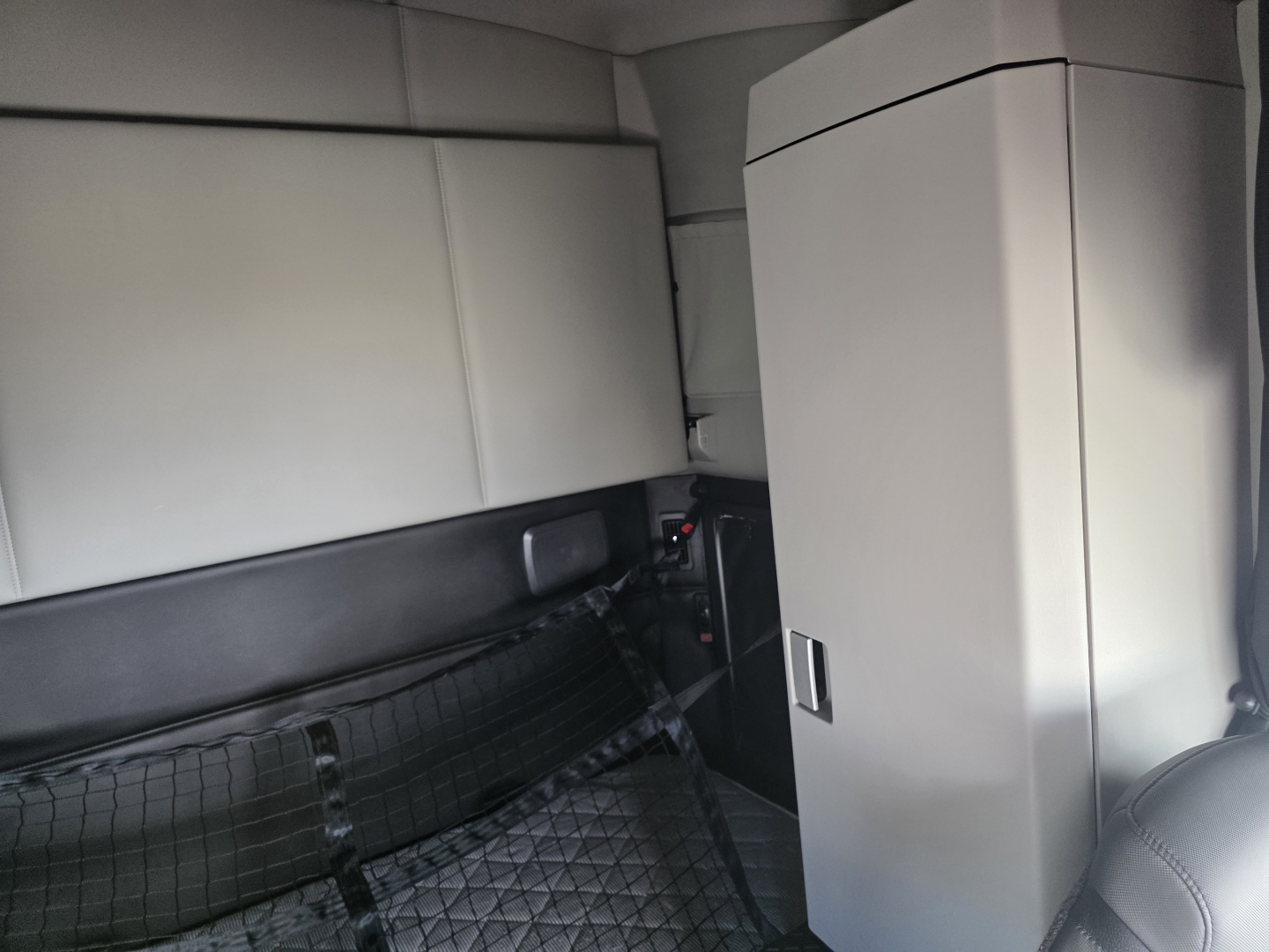 Kenworth T680 interior cargo area showing storage cabinet and passenger seat in-vehicle view.