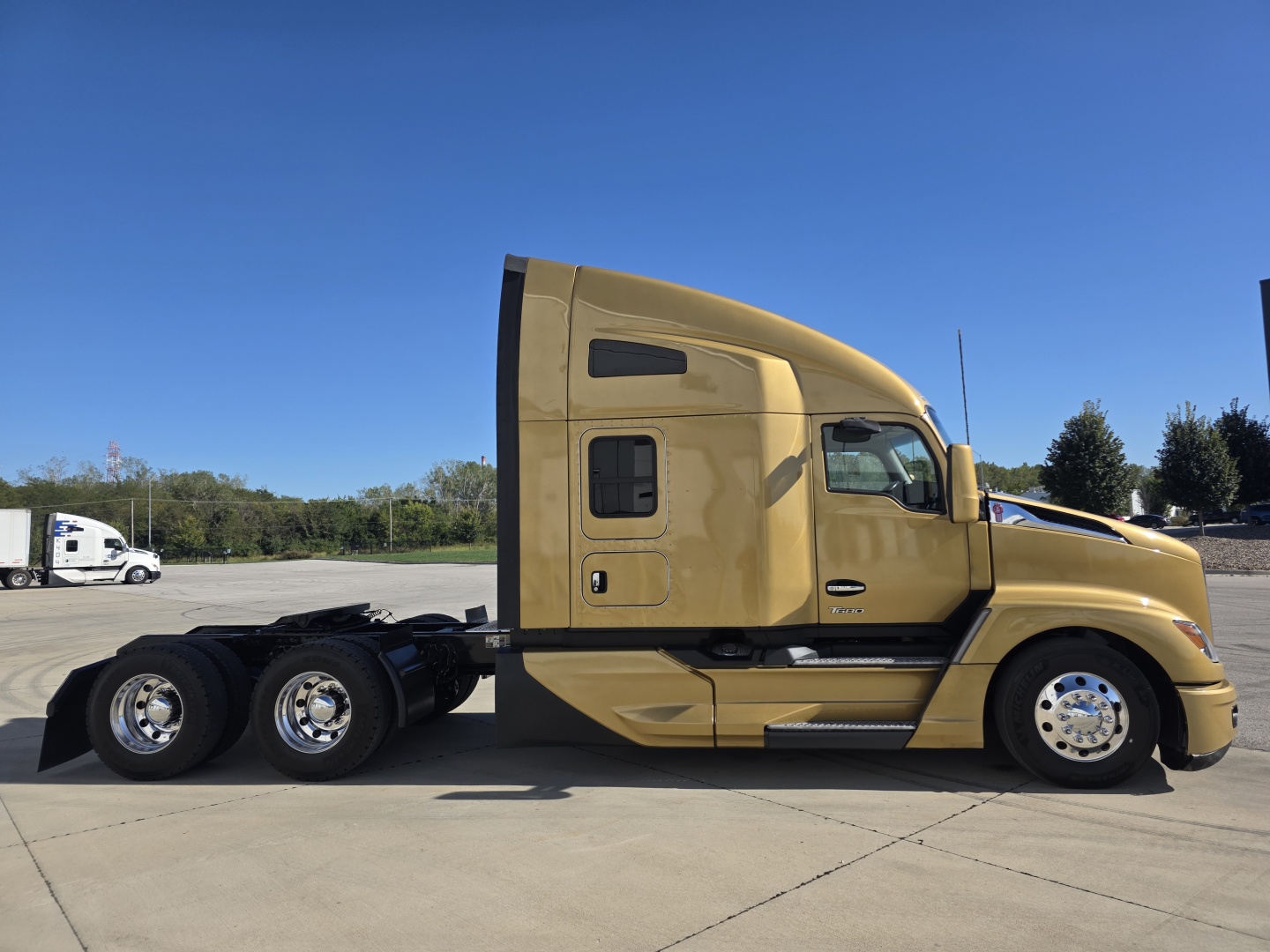 Kenworth T680 tractor in gold color side view showing sleeper cab and rear axles.