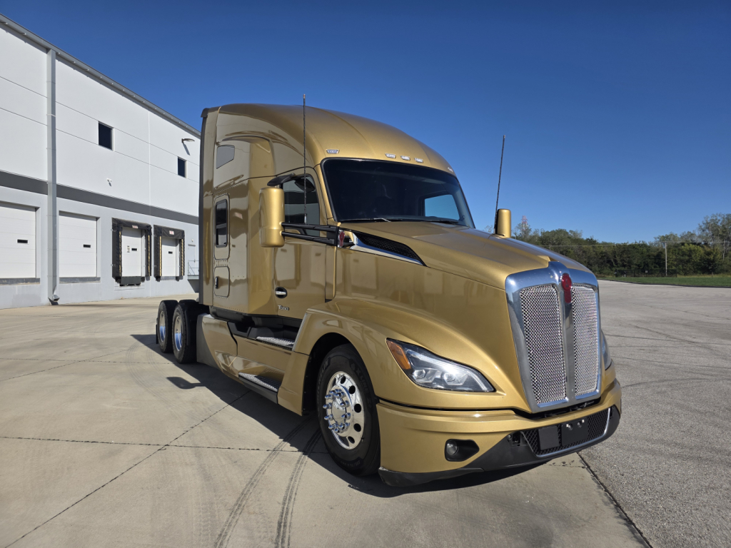 Kenworth T680 conventional sleeper truck from front-left view showing gold paint and chrome grille.