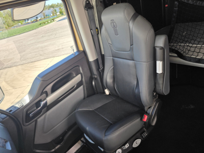 Kenworth T680 truck interior seat and door area; visible text on seat back shows Kenworth logo; no other legible markings or labels.