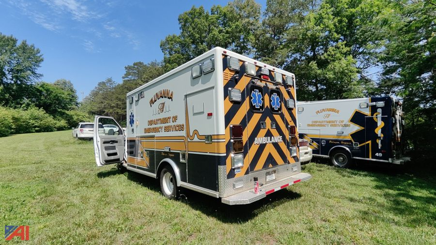 Ambulance rear view with chevron pattern and text 'Ambulance' on the back, side text indicates 'Fire Department' and 'Ambulance' services; another ambulance visible in background