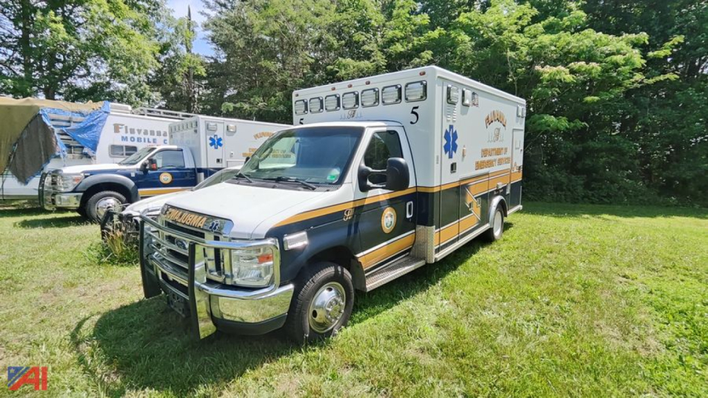 2017 Ford E450 ambulance with white cab and yellow/gray body. Ambulance markings and medical symbols visible on side. Front grille and bumper, emergency lights on roof interior visible.