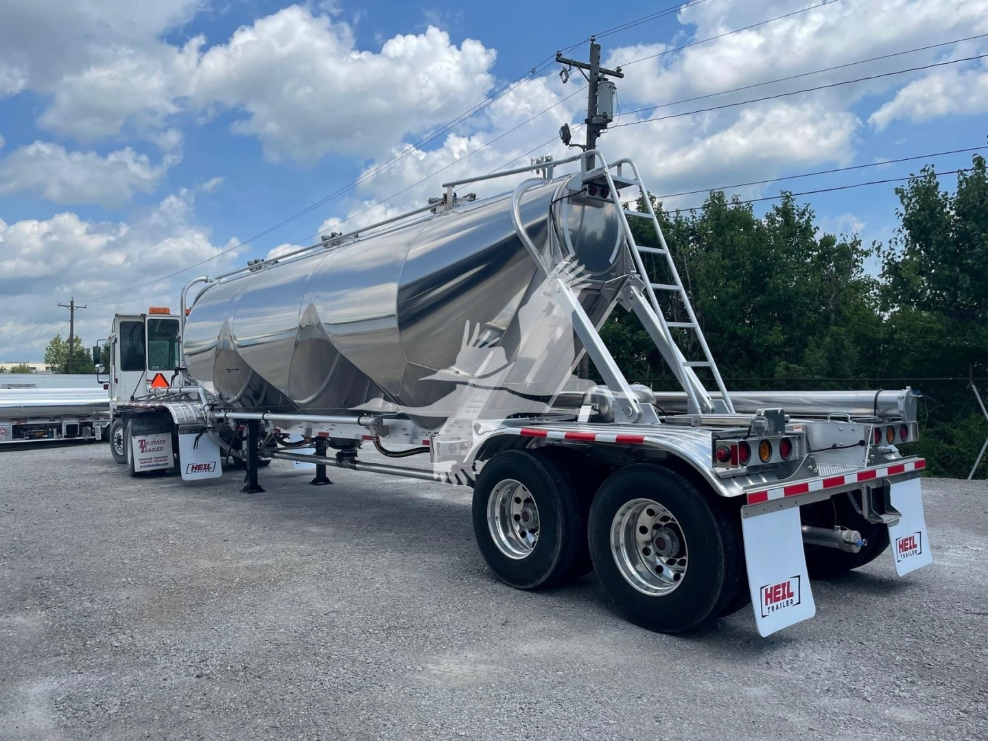 Heil Super Jet 1040 pneumatic dry bulk trailer in silver, tandem axle, chrome finish, rear wheels with mud flaps, ladder and top hatch visible.