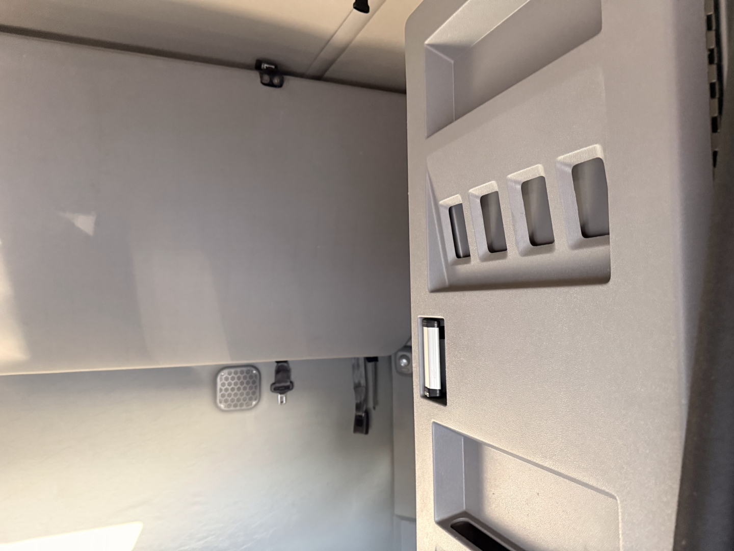Tractor truck cab interior with door open showing storage pockets on the door and footboard area.