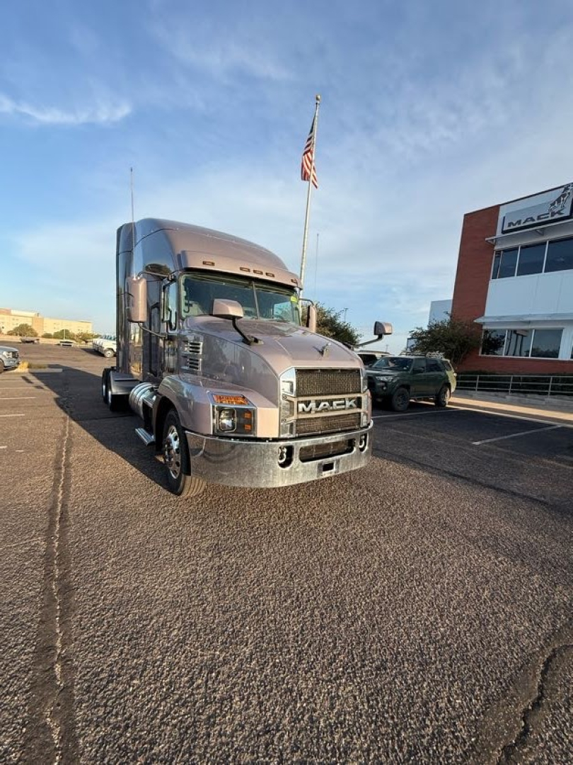 Mack AN64T70 conventional sleeper truck front view in parking lot with flag, showing Mack grille and headlights.