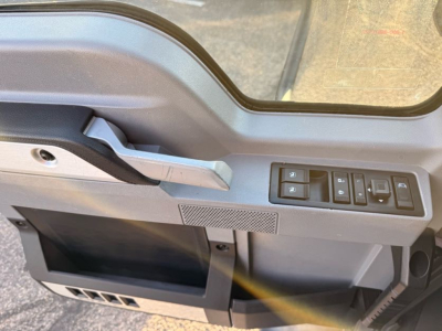 Mack truck cab interior showing window controls and driver-side door panel with armrest and storage pocket.