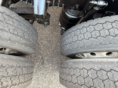 Drivetrain area of a Mack AN64T70 showing rear dual tires, suspension components, and drivetrain tubing. Close-up view of the wheel wells and frame.