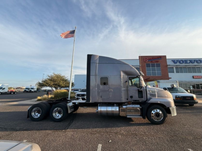 Truck side view showing 2023 Mack AN64T70 conventional sleeper with chrome fuel tanks and dual rear axles.