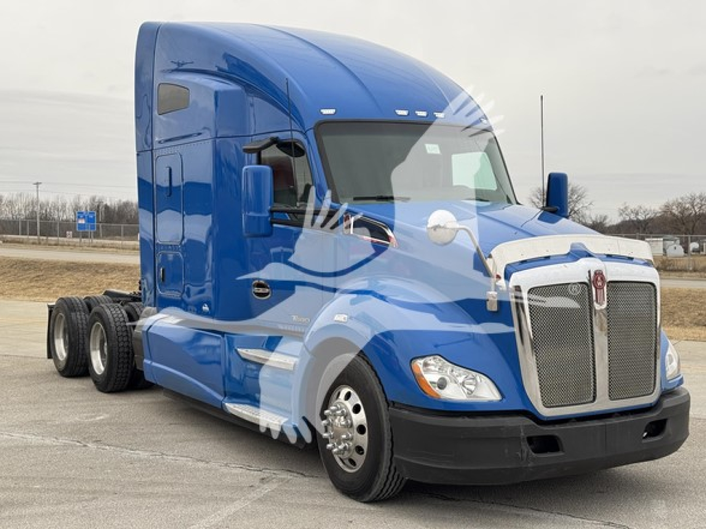 Kenworth T680 2016 blue conventional sleeper truck from a side-front angle showing cab and front grille with dual rear axles, stock number 1905115-D_APU.