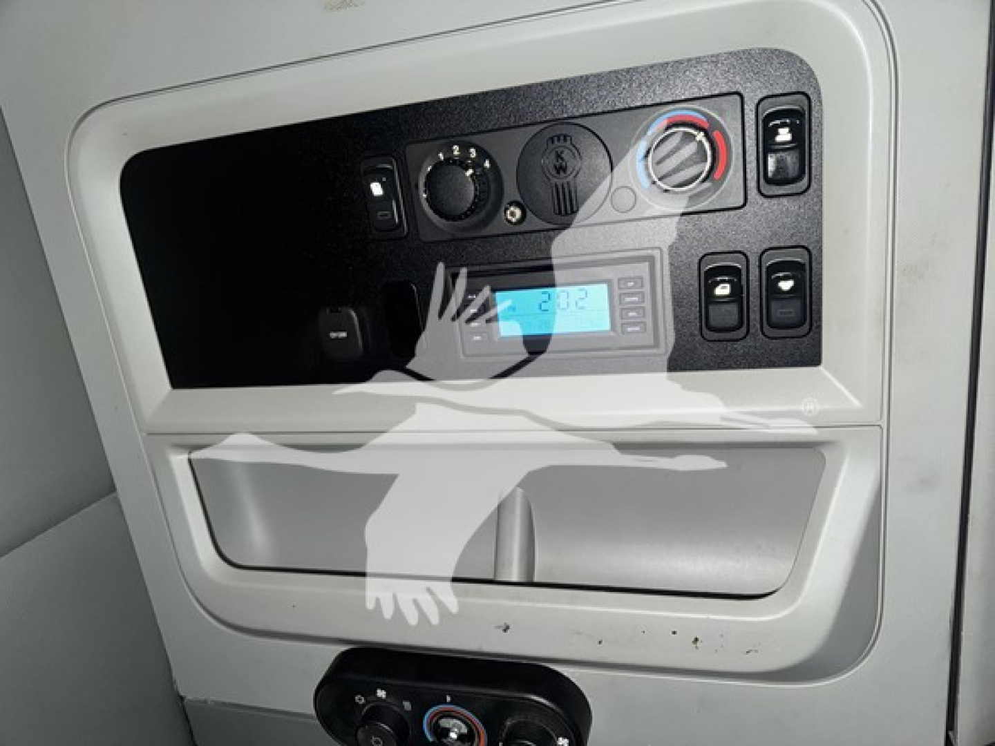 Dashboard panel of a Kenworth T680 showing climate control dial, digital display, and small storage pocket.