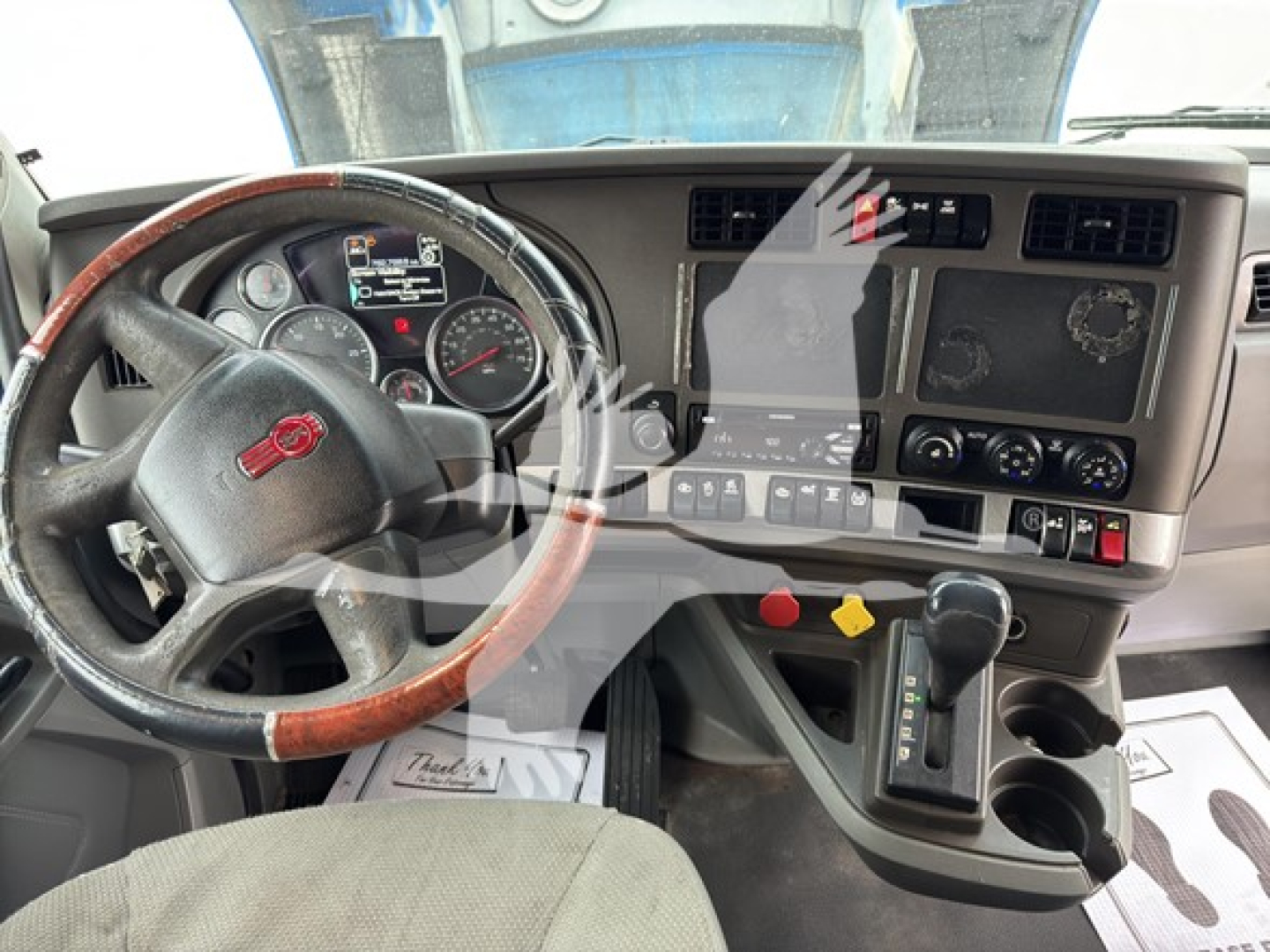 Kenworth T680 truck interior view showing steering wheel, dashboard gauges, center console with gear shifter, and control panels.