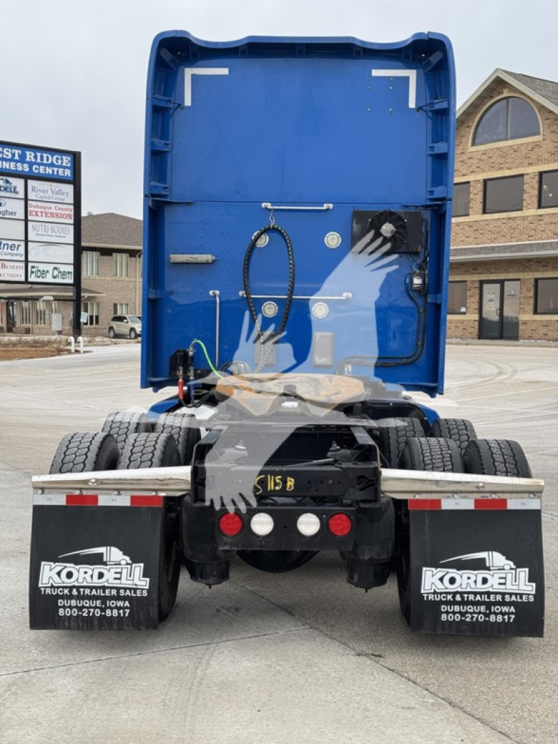 Kenworth T680 rear view showing cargo area interior and back of sleeper, with dual rear wheels, mudflaps, and bumper; visible hoses and components in the open truck bed.