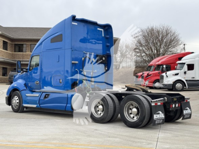 Kenworth T680 tractor unit with blue sleeper cab and three rear axles, side view, showing chassis and wheels.
