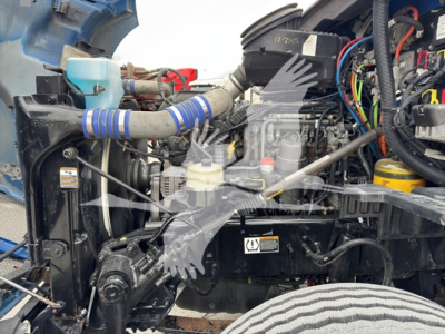 Kenworth T680 engine bay view showing hoses, wiring harness, and various fluid reservoirs and components.