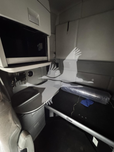 Cab interior of 2016 Kenworth T680 showing storage area, overhead compartments, and a padded bunk/seat with a rolled insulation sleeve. Visible text not legible beyond generic interior features.