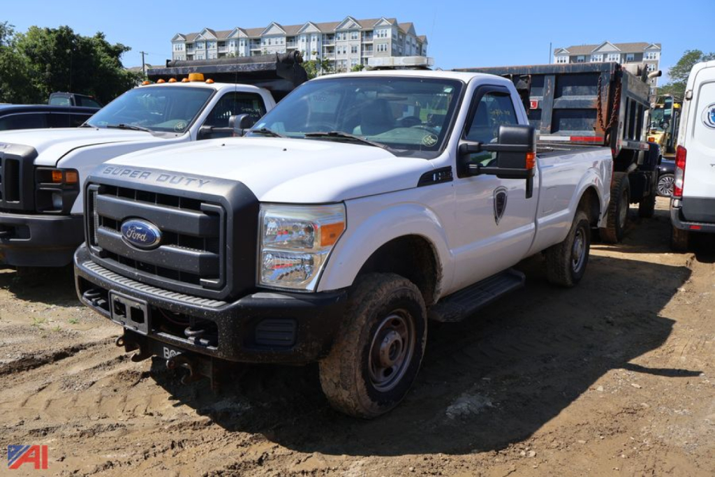 Ford F-250 Super Duty pickup truck with plow attachment in a gravel lot, white crew cab, front grille badge visible.