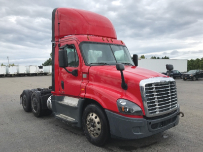 Red Freightliner Cascadia125 daycab tractor showing front and side with chrome grille and raised sleeper cab