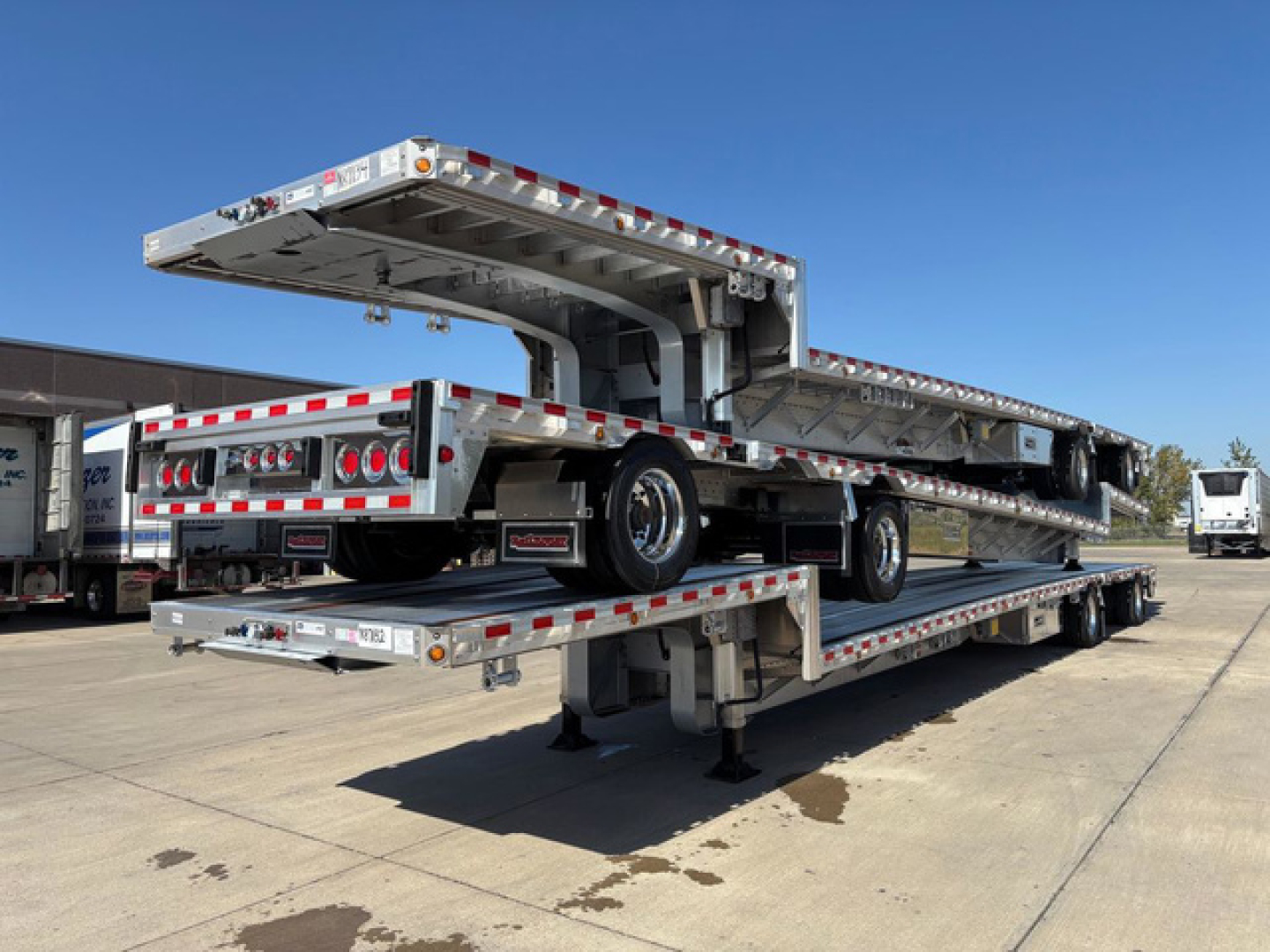 Dropdeck trailer in stacked position showing dual-level loading platform and end ramps, aluminum deck, reflective tape, and support legs.