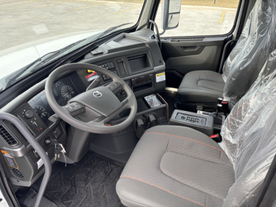 Volvo VHD64B300 cab interior showing steering wheel, dashboard, and central console with seats and plastic seating covers.