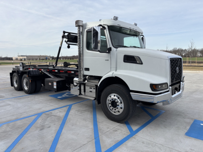 Volvo VHD64B300 roll-off truck in white, side view showing cab, chassis, and undercarriage with hooklift system.