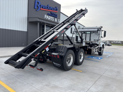 Volvo VHD64B300 roll-off truck showing loading container on rear chassis with elevated ramps and wheel configuration.