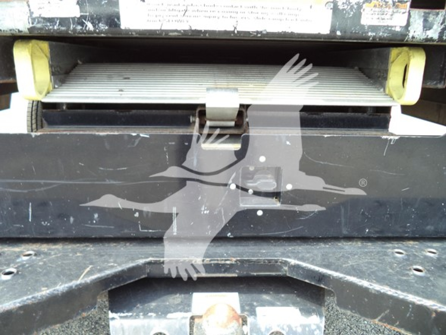 Ford E-350 cutaway rear step with label area and bumper, showing a metal step platform and black body with yellow supports.