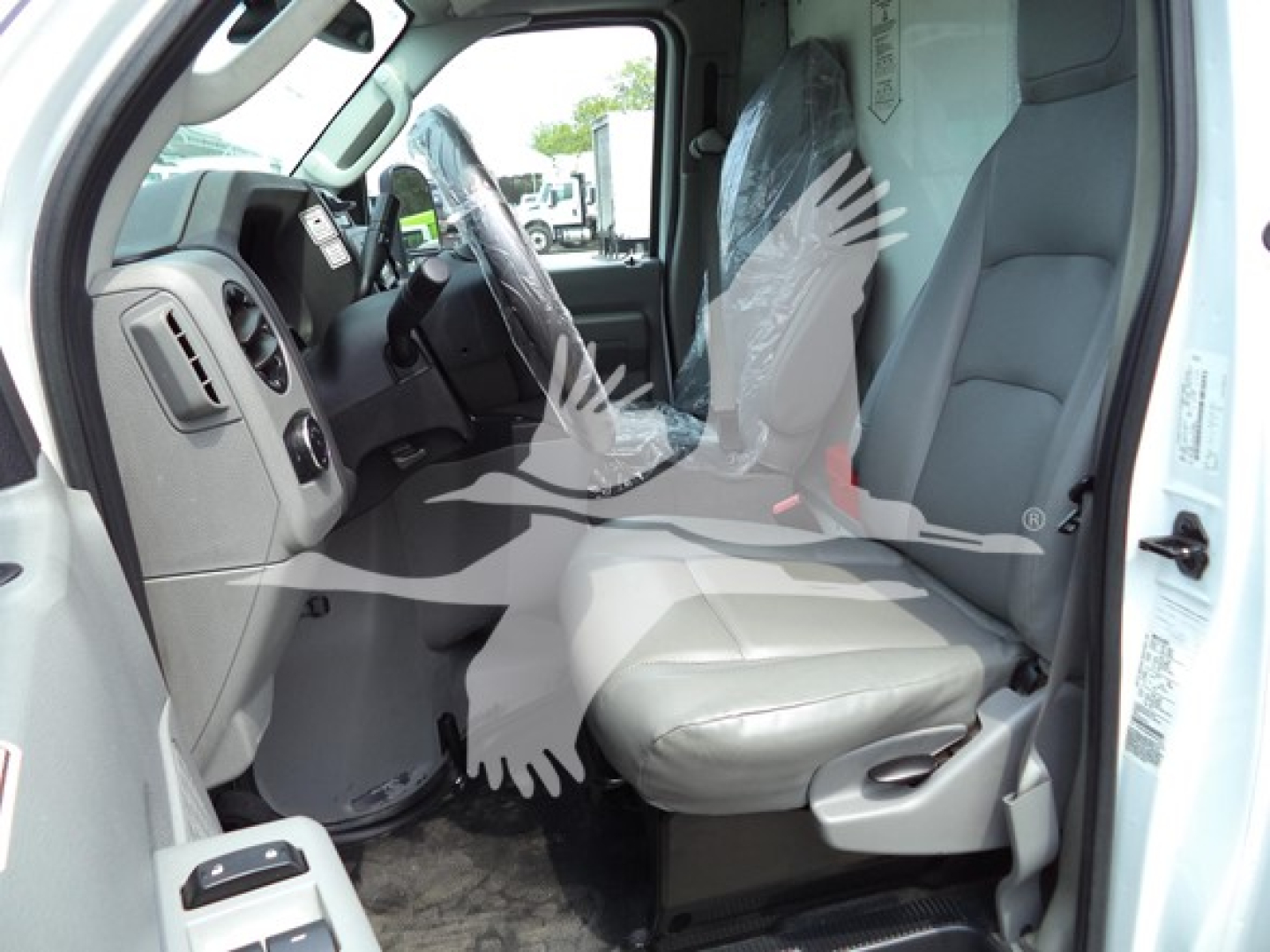 Ford E-Series van interior showing driver and front passenger seats with gray fabric, steering wheel, and dashboard,