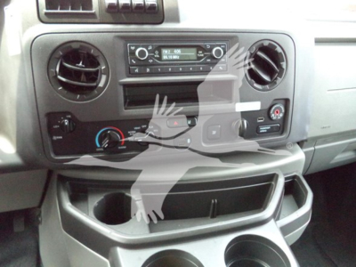 Ford E-Series cargo van dashboard with central radio, two circular vents, climate controls, and cup holders visible.