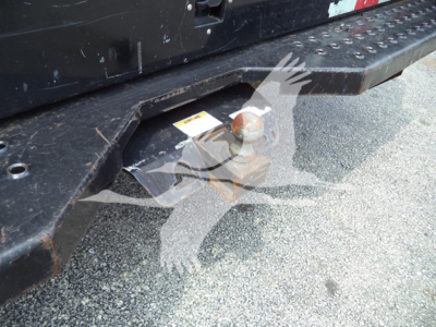 Ford E-350 tail area showing hitch ball and step bumper with textured metal surface and a small warning label unreadable