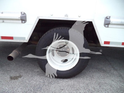 Ford E-350 wheel and rear cargo area showing wheel, tire, and side panel with stock hardware.