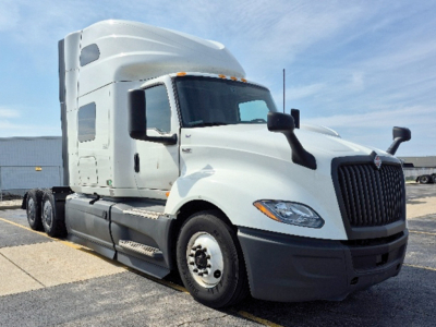 Truck cab with sleeper showing International LT625, front chrome grille, white exterior, black mirrors, and large tires.