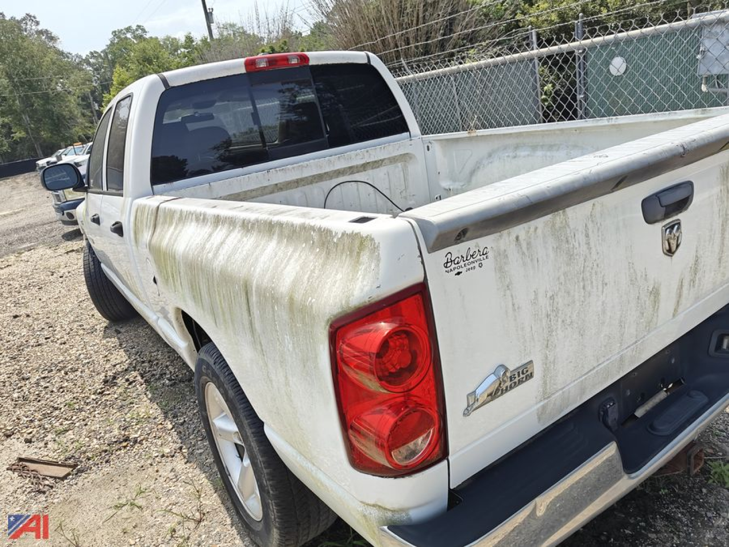 Dodge Ram 1500 crew cab pickup truck rear view showing a light-colored bed with dirt/soil and tailgate emblem.