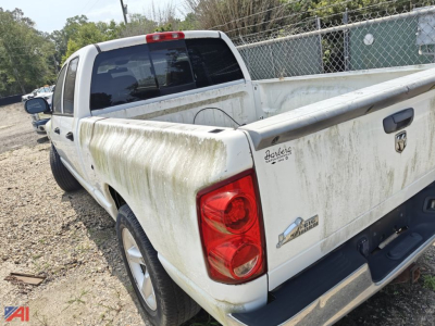 Dodge Ram 1500 crew cab pickup truck rear view showing a light-colored bed with dirt/soil and tailgate emblem.