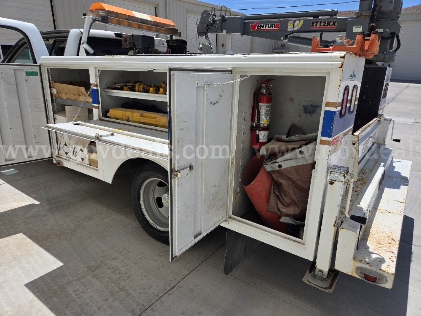 Back-right side view of a 2009 Chevrolet Silverado 3500HD utility/service truck with mounted tool storage compartments, fire extinguisher, and ladder rack.