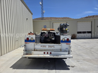 Rear view of a service truck with a mounted crane and equipment on bed, labeled FIRE DEPT. and 4035, in an industrial yard.