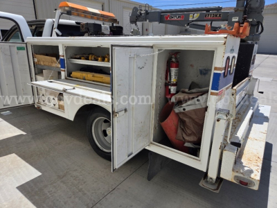 Back-right side view of a 2009 Chevrolet Silverado 3500HD utility/service truck with mounted tool storage compartments, fire extinguisher, and ladder rack.