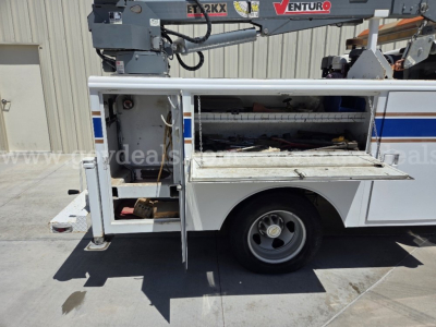Service/utility truck bed with open compartments on a 2009 Chevrolet Silverado 3500HD, hydraulic lift arm visible above, stock number 9764-25, VIN 1GBJK79619E130307.
