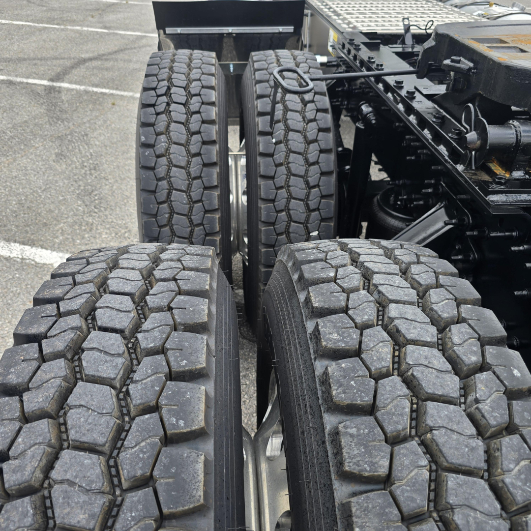 Four rear truck tires on a Mack PI64T tractor showing tread pattern and wheel hubs.