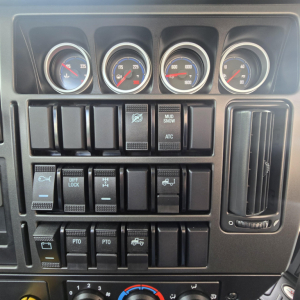 Dashboard cluster and control panel of a Mack PI64T truck showing multiple gauges and switches including mud/snow, ATC, diff lock, PTO, and cruise controls