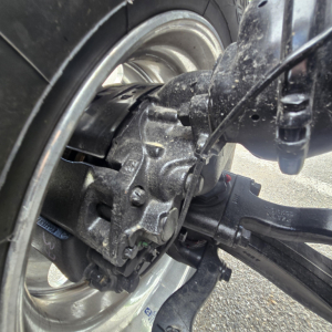 Front drive axle of a 2027 Mack PI64T truck showing wheel hub, brake caliper, and suspension components.